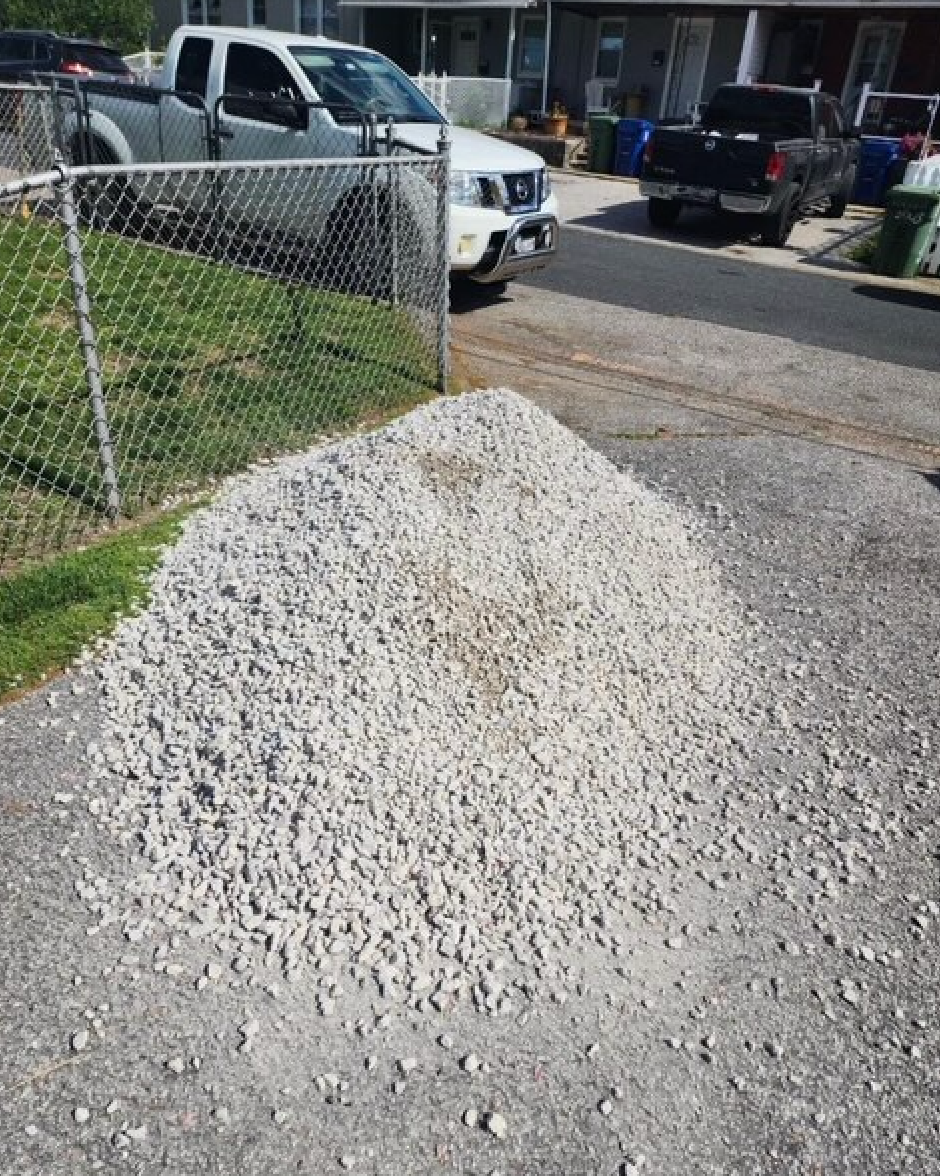 A pile of gravel is sitting in front of a chain link fence.