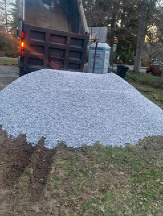 A pile of gravel is sitting in front of a dump truck.