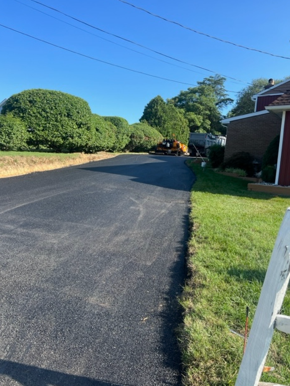 A ladder is sitting on the side of a road next to a house.