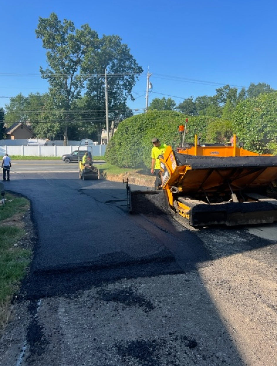 A group of men are laying asphalt on a road.