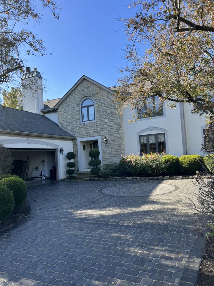Two-story house with a stone facade, a circular driveway, and a garage under a white tower.