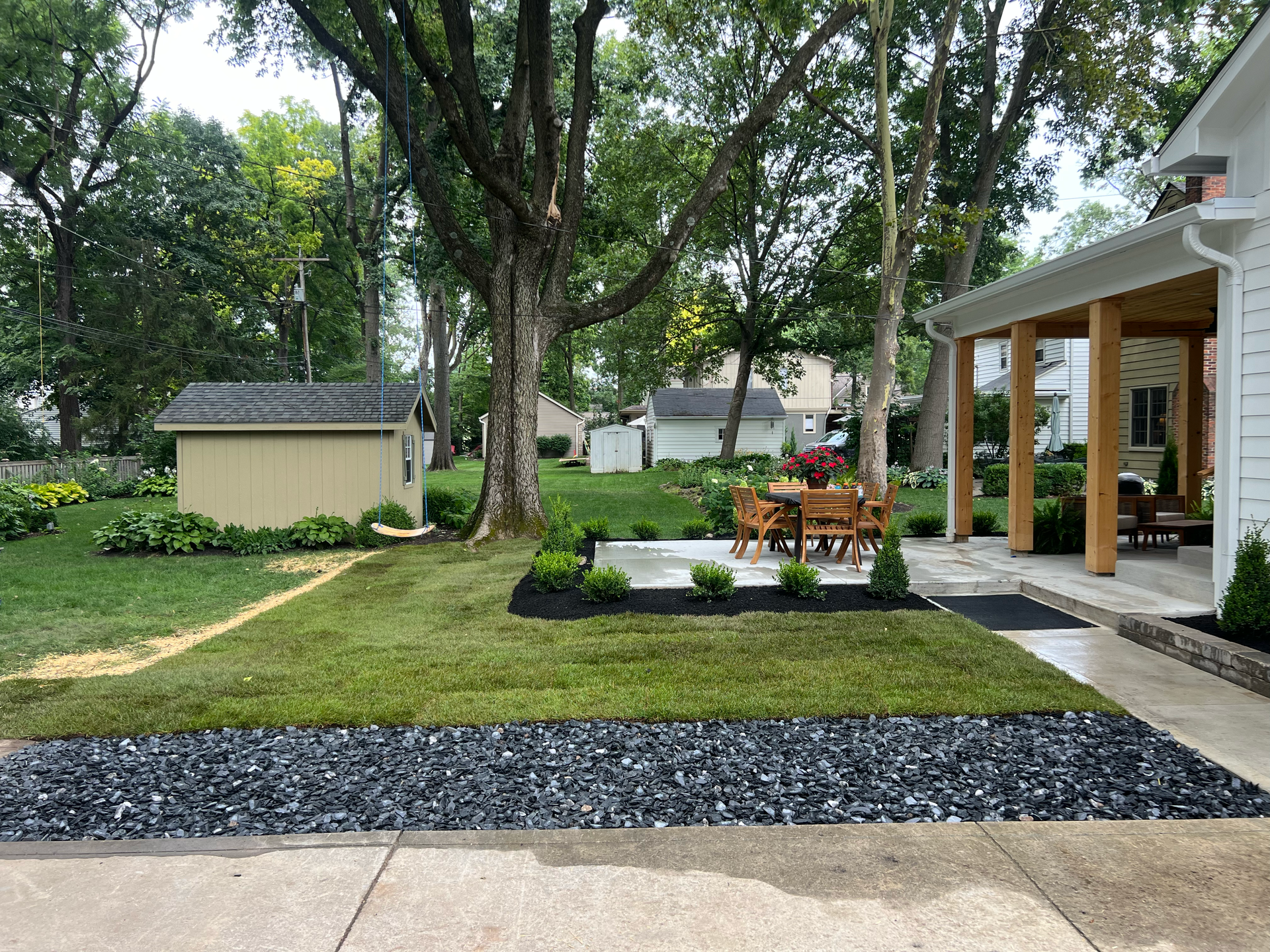 Lawn and garden with a shed, patio with seating, and house with a porch.