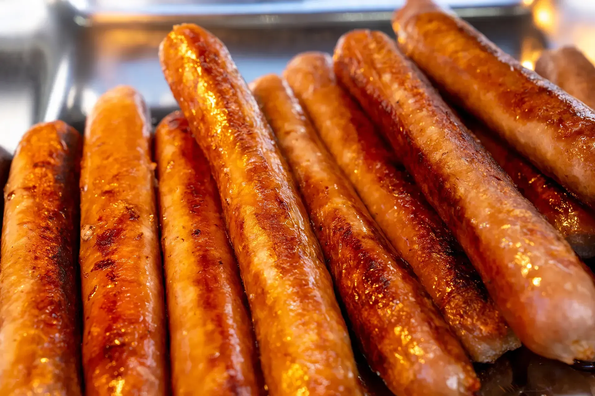 A bunch of sausages are sitting on top of each other on a tray.