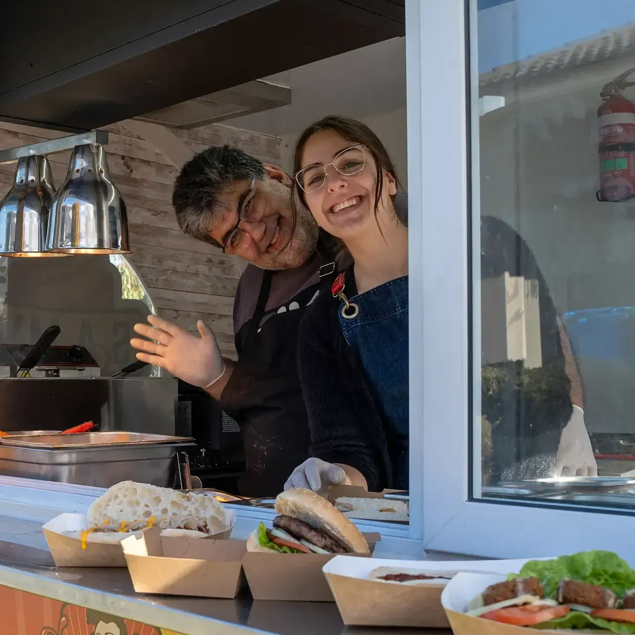 A man and a woman are standing in front of a food truck