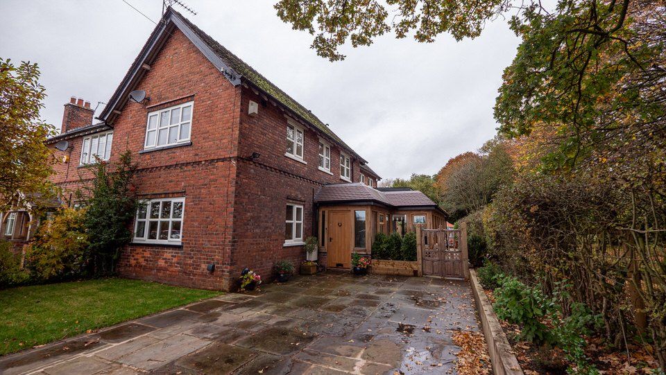 Single-storey oak-frame extension with landscaped garden and York stone-paved driveway in Cheshire home by Rawlinson Construction