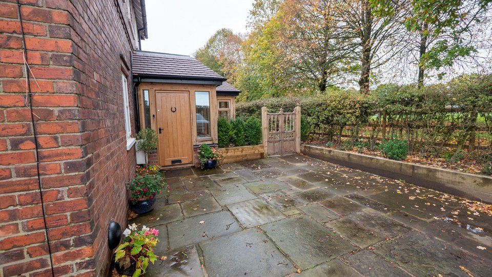 Exterior shot highlighting modern oak-frame extension with landscaped grounds and driveway by Rawlinson Construction