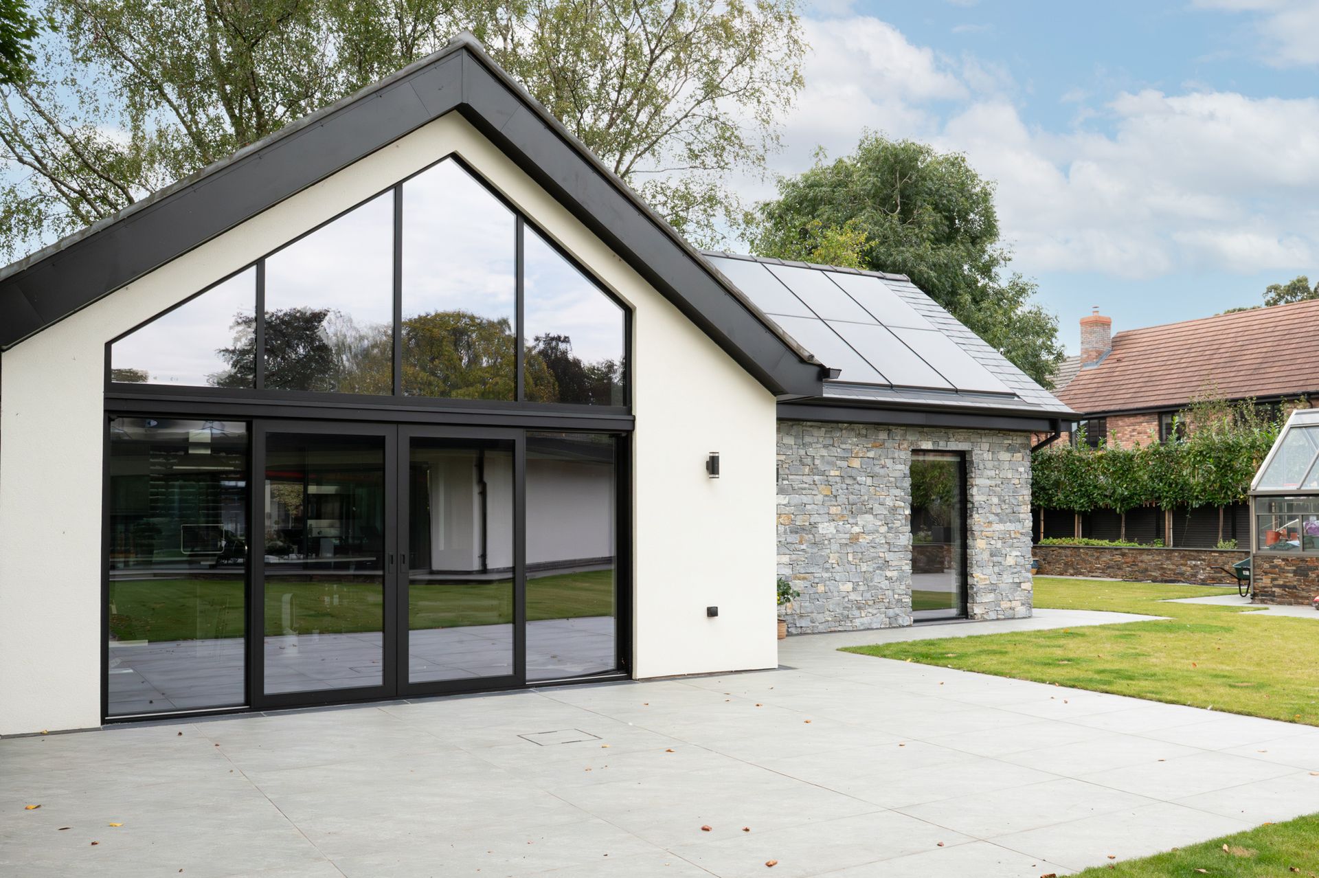 Exterior view showcasing outbuildings and contemporary finishes of Cheshire property built by Rawlinson Construction