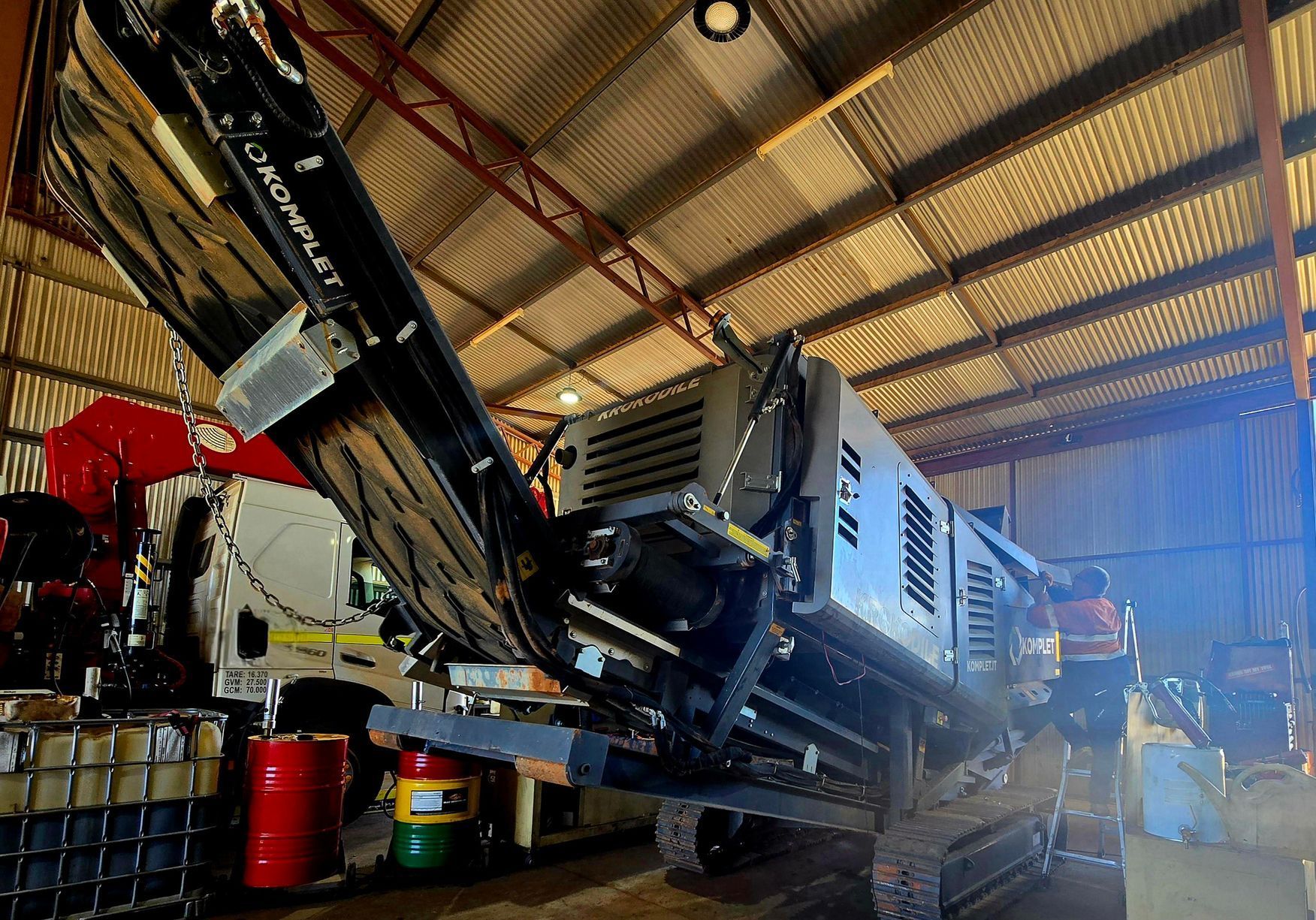 A Man Is Standing In A Warehouse Working On A Truck — Central Diesel Services In Alice Springs, NT