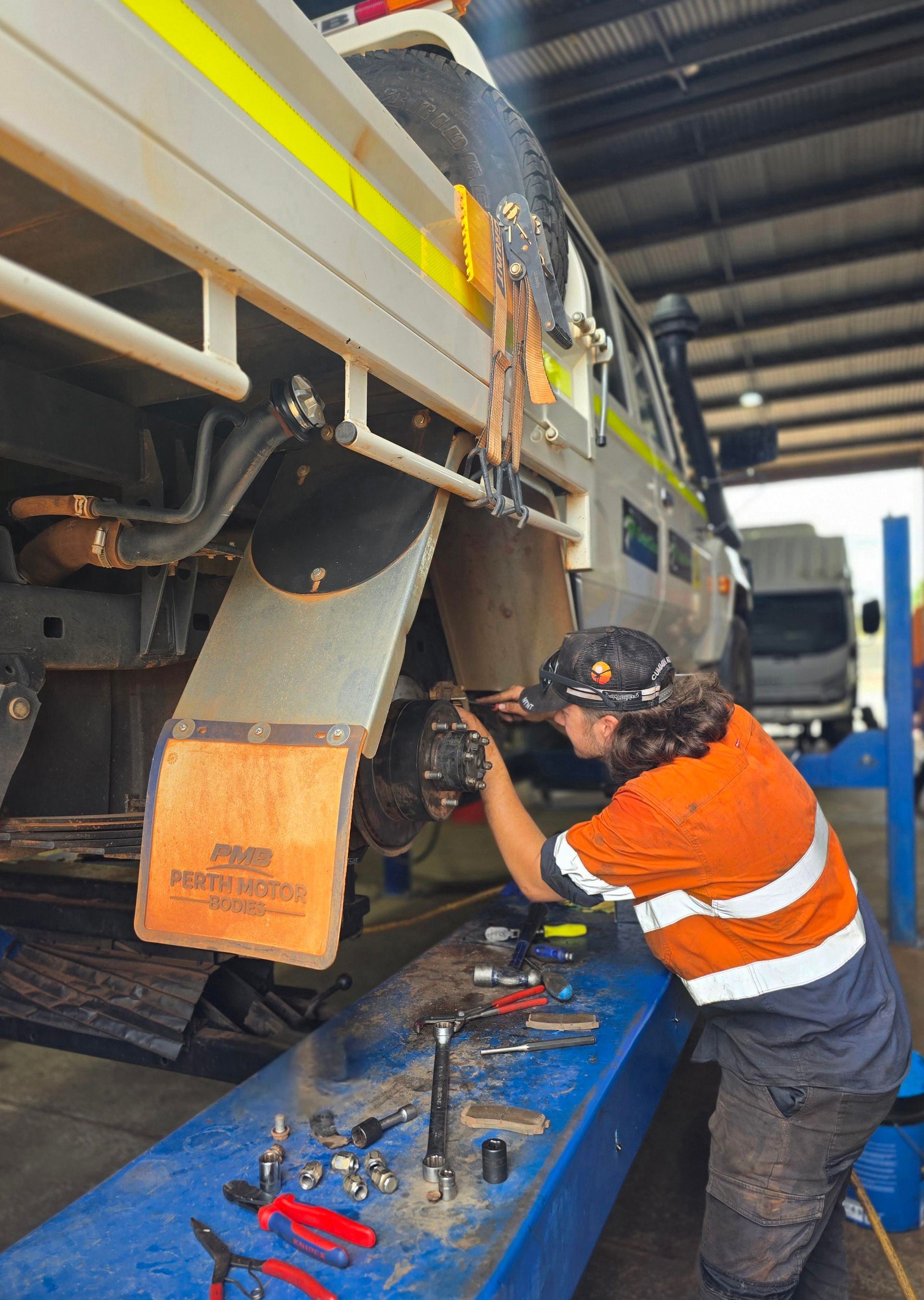 A Man Is Working On The Underside Of A Truck In A Garage — Central Diesel Services In Alice Springs, NT