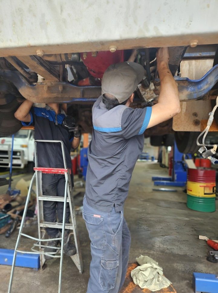 A Man Is Working Underneath A Car In A Garage — Central Diesel Services In Alice Springs, NT