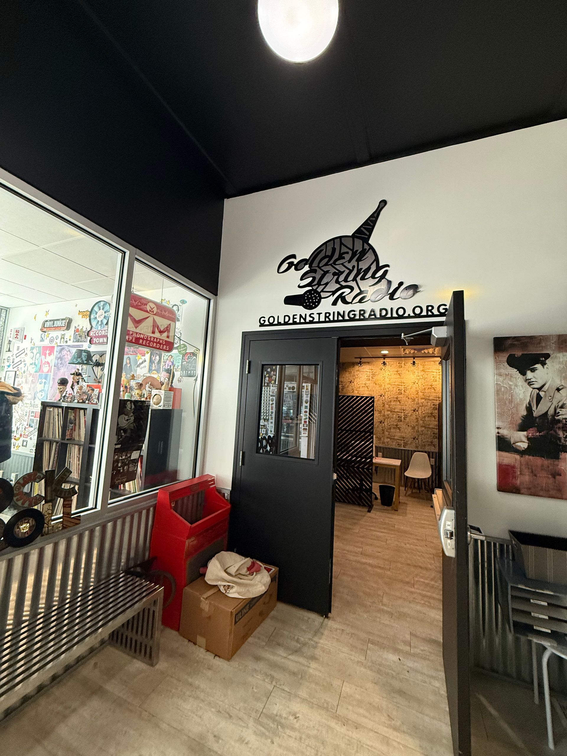 Entrance to business with black door and sign; bench and windows to the left.
