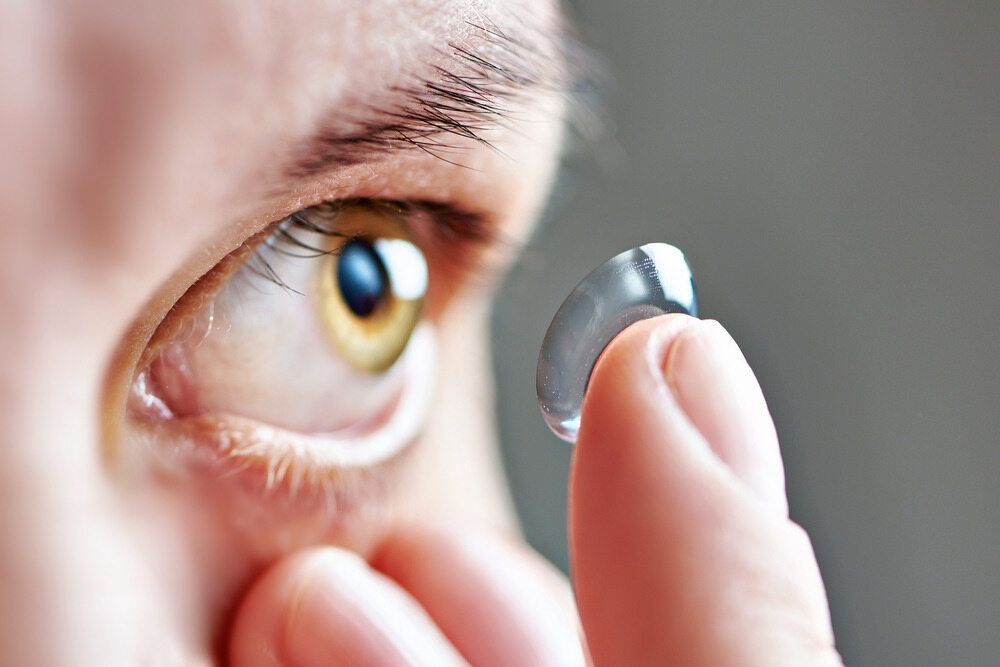 A Person Is Putting A Contact Lens In Their Eye — Eye Supply In Mareeba, QLD