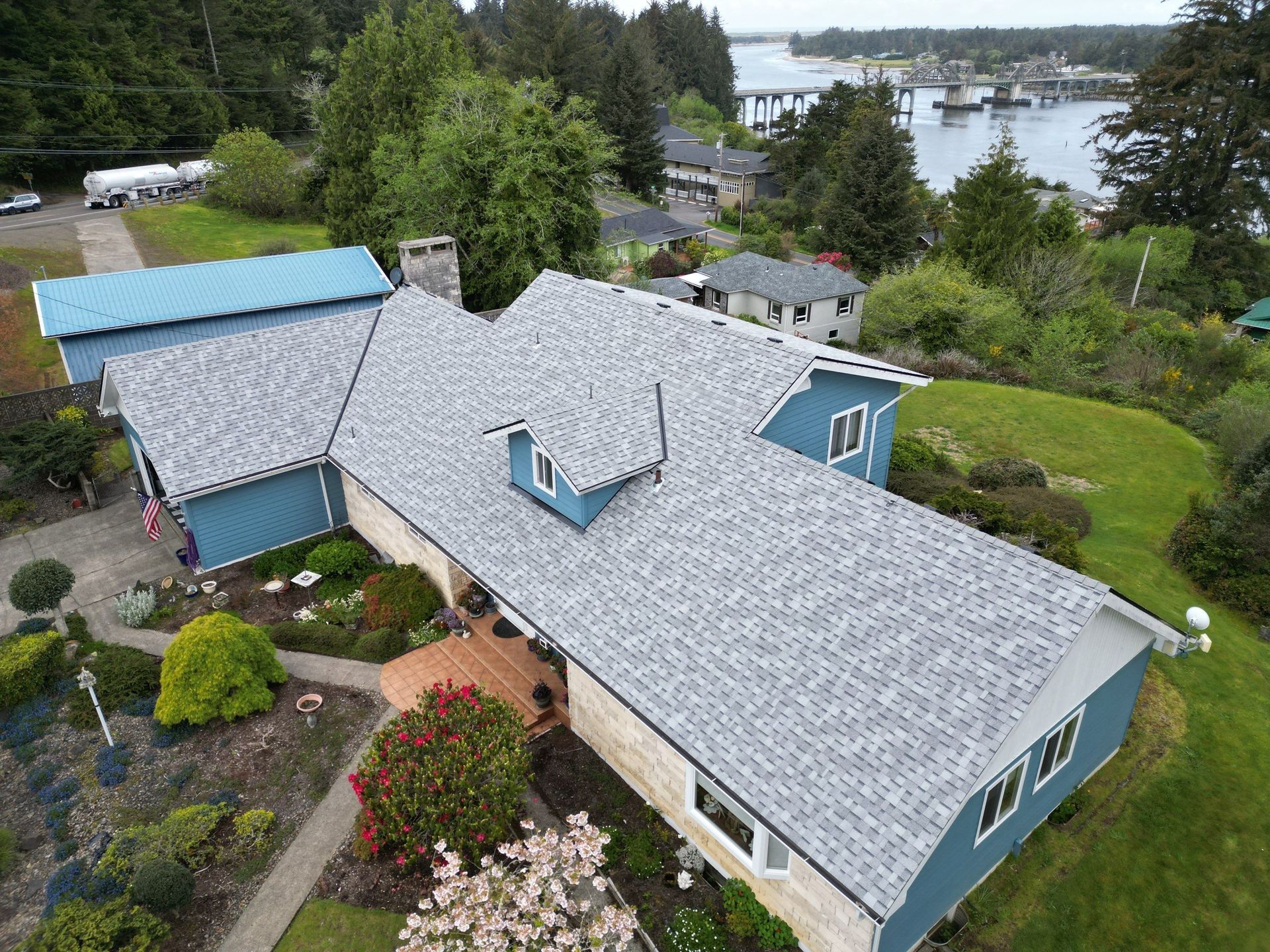 An aerial view of a large house with a gray roof surrounded by trees.