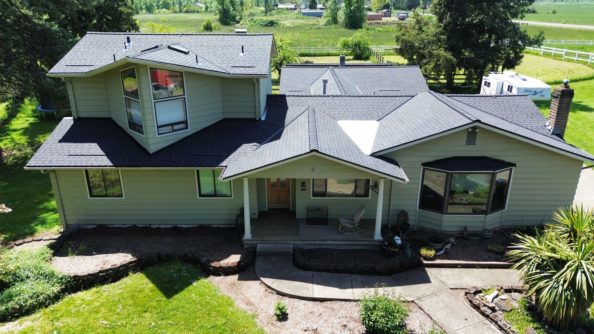 An aerial view of a house with a gray roof surrounded by trees.