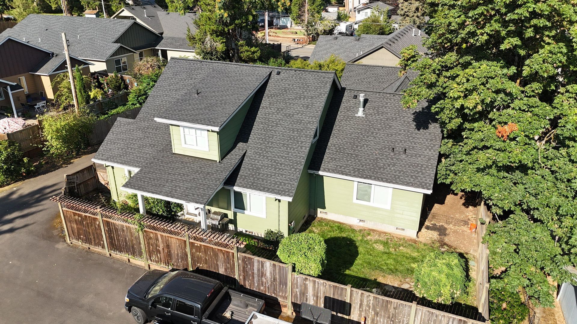 An aerial view of a green house with a black truck parked in front of it.