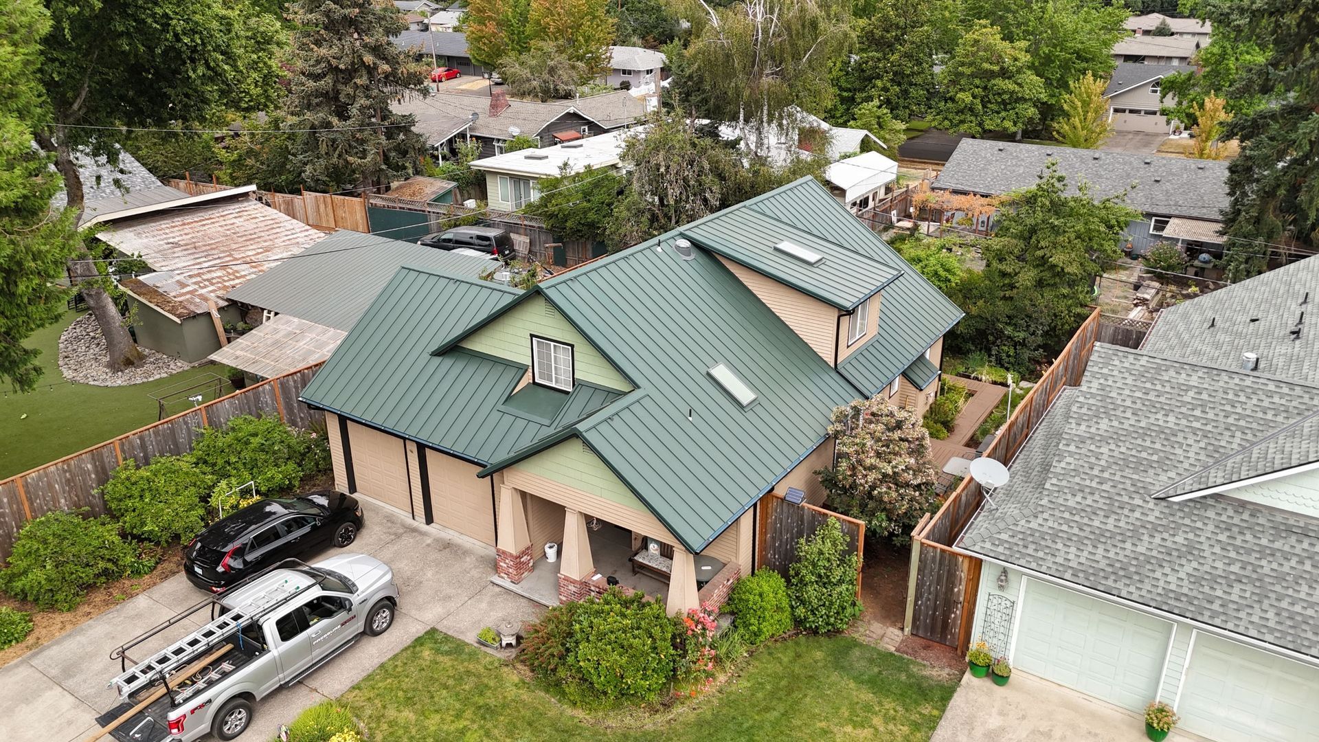 An aerial view of a house with a gray roof surrounded by trees.