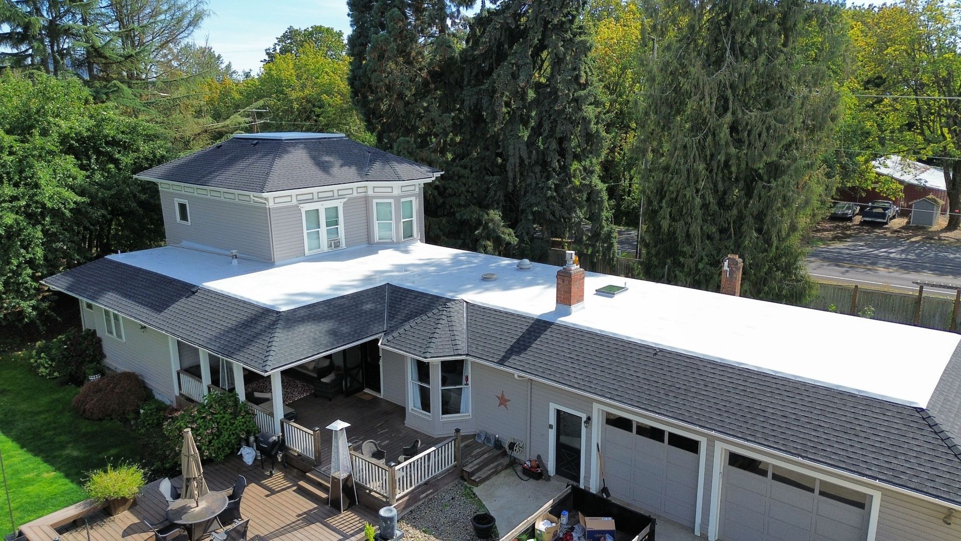An aerial view of a large white house with a black roof surrounded by trees.