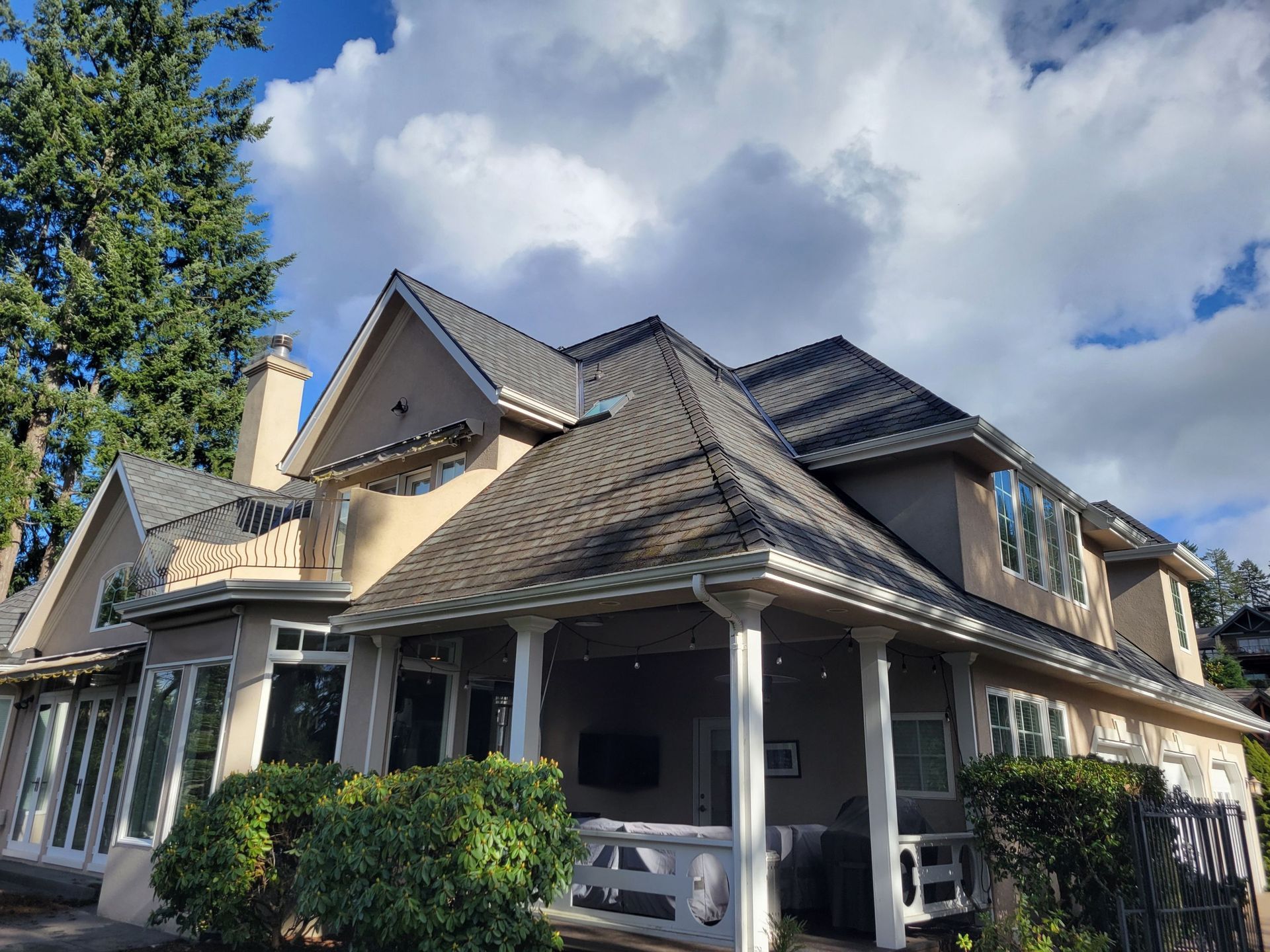 A large house with a porch and a gray roof.