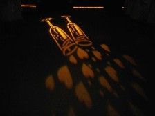 Two champagne glasses and heart shapes projected on a dark surface.