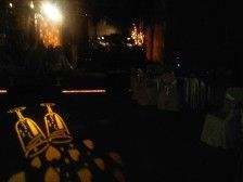 Dark room with champagne glasses projected on floor, and a stage illuminated in the background.