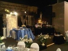 Wedding reception with blue table, flowers, DJ booth, and stage with lights.