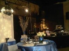 A decorated event space with a table in blue, flowers, and a disco ball.