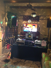 DJ setup with turntables, speakers, TV, disco balls, and a black table. Party setting.