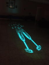Glowing blue champagne glasses projected onto a dark floor, casting a patterned shadow.