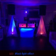 DJ setup with speakers, booth, and colorful lights. Black and blue tones with a $30 black light effect.