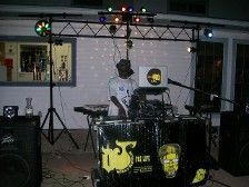 DJ at an outdoor event, playing music with lights and speakers set up.