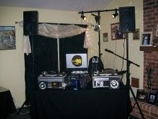 DJ setup with turntables, speakers, and a microphone on a black table, indoors.