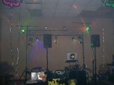 DJ setup with speakers, lights, and equipment in a dimly lit room.