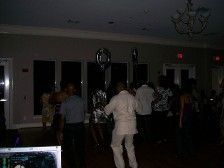 People dancing in a dimly lit event space with balloons.
