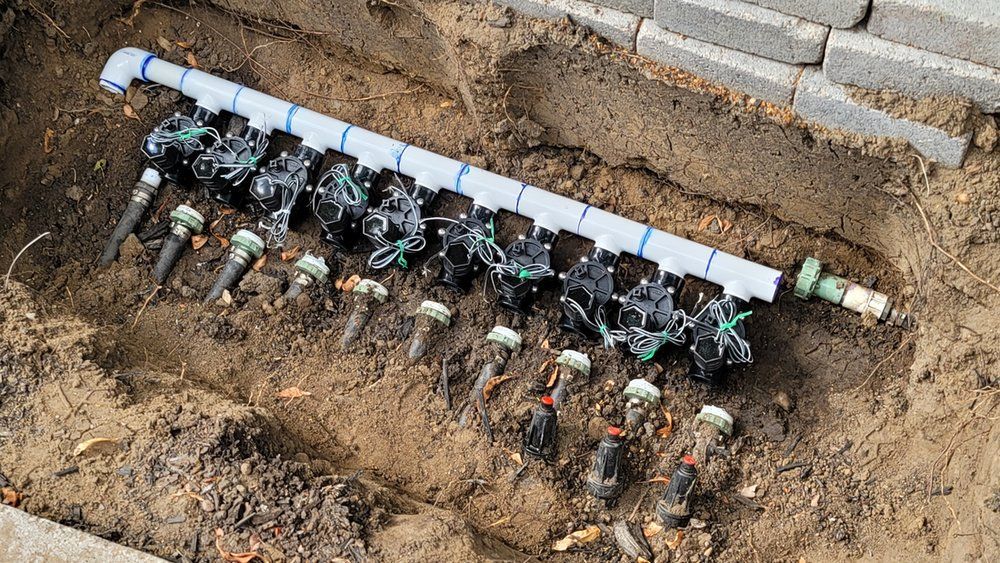 A row of sprinklers are sitting in the dirt.