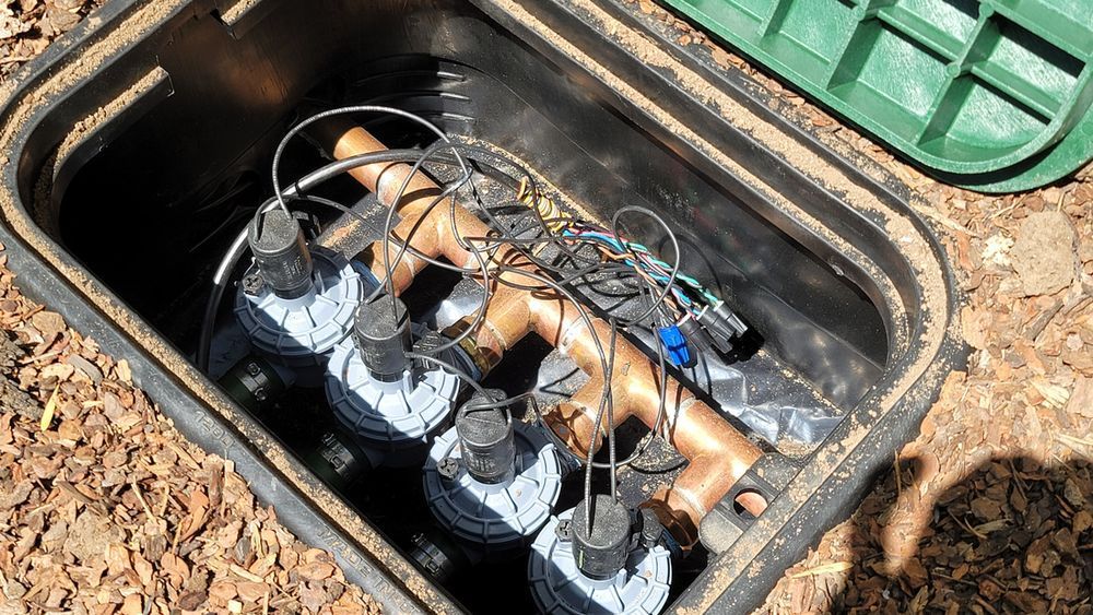 A box filled with water meters and wires is sitting on the ground.