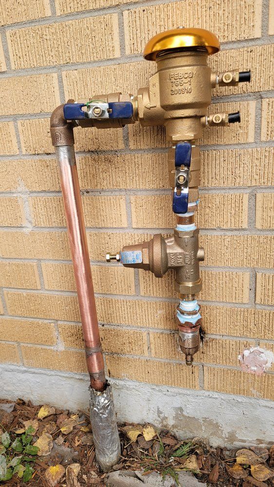 A copper pipe is attached to a brick wall.