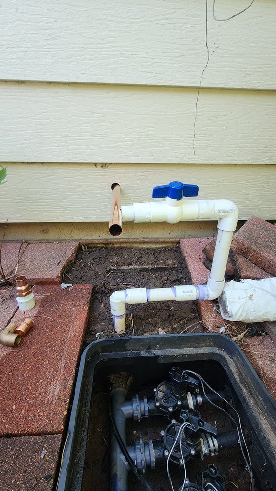 A sprinkler system is being installed on the side of a house.