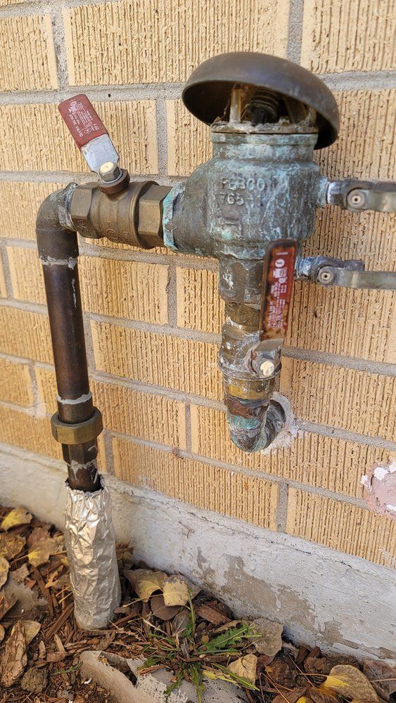 A close up of a water valve on a brick wall.