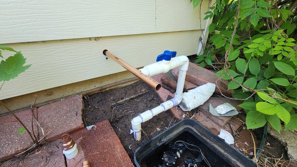 A pipe is laying on the ground next to a brick wall.