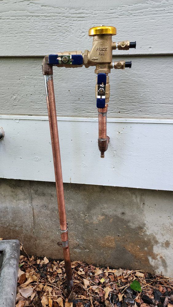 A copper pipe is attached to a faucet outside of a house.