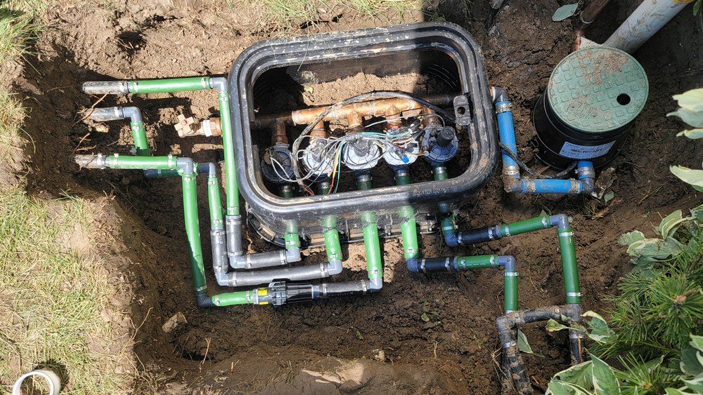 A box with a bunch of pipes coming out of it is sitting in the dirt.