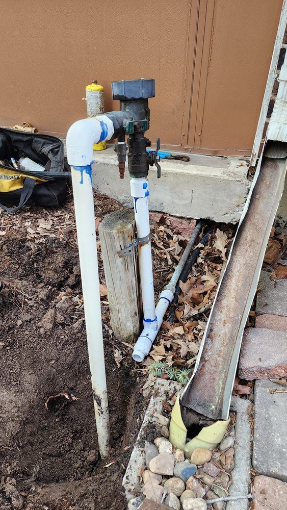 A water pipe is sitting in the dirt next to a ladder.