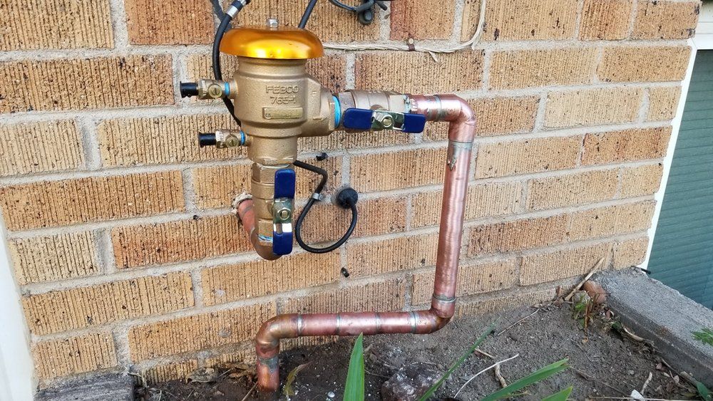 A copper pipe is attached to a brick wall.