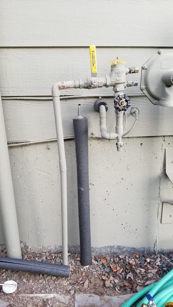 A gas valve is attached to a wall next to a hose.