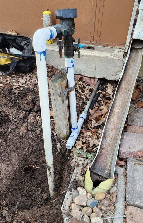 A pipe is being installed in the dirt next to a wooden post.