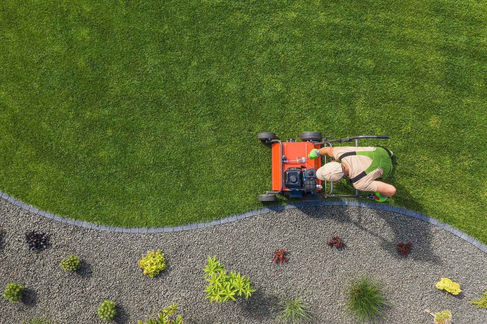 An aerial view of a person riding a lawn mower on a lush green lawn.