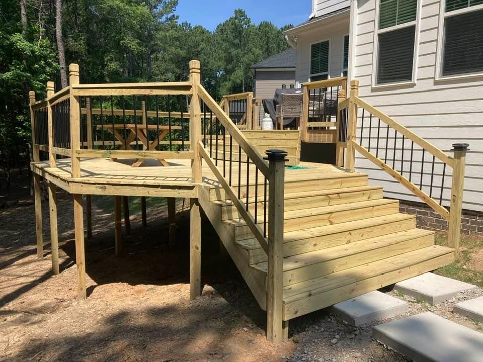 Wooden backyard deck and ramp with stairs beside a house, leading to a raised platform.