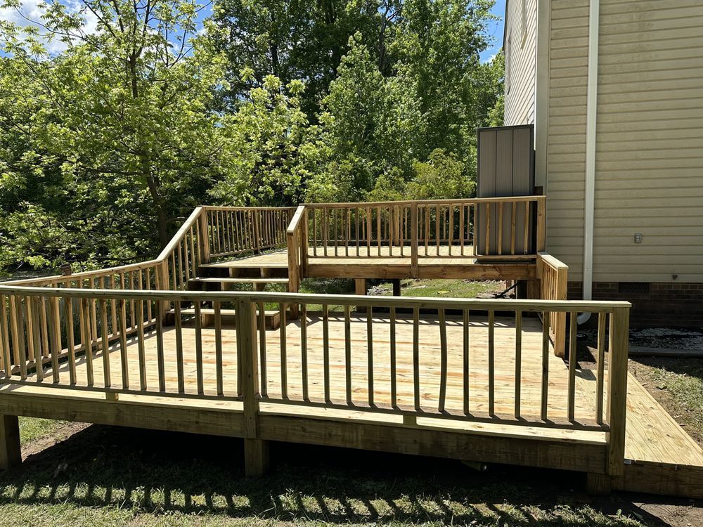 Wooden accessibility ramp and platform with railings beside a house, surrounded by trees.