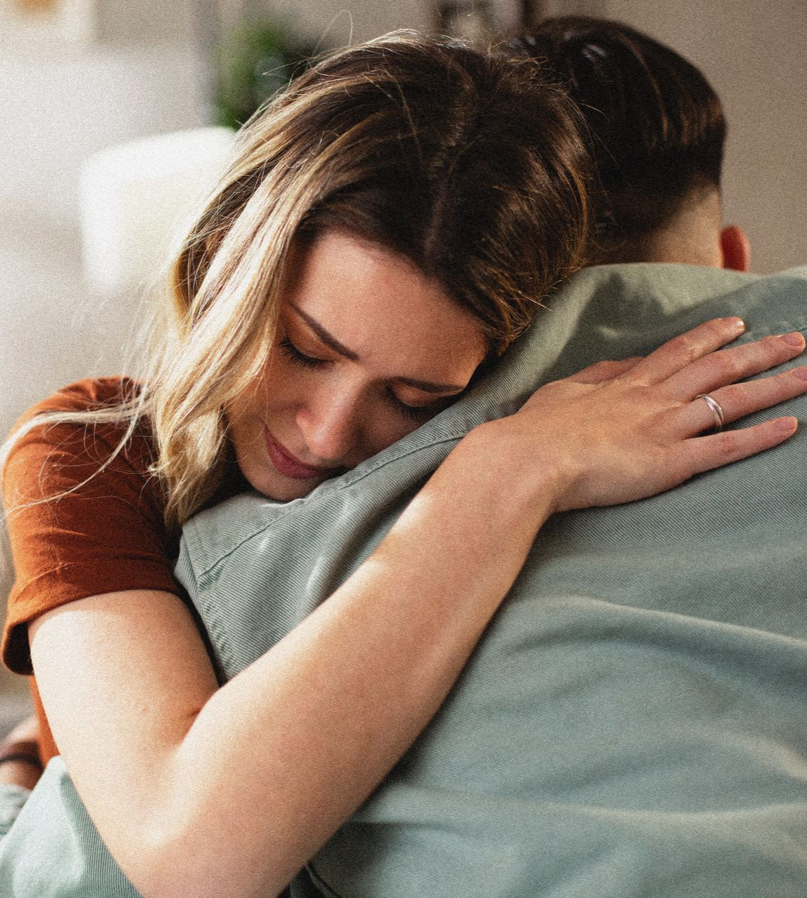 Deux personnes enlacées à l'intérieur, l'une posant sa tête sur l'épaule de l'autre