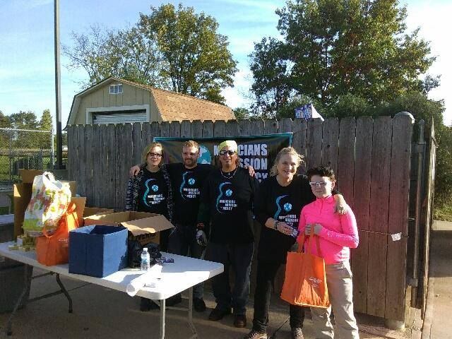 A group of people are posing for a picture in front of a wooden fence.